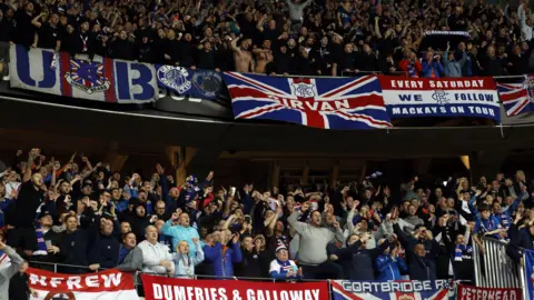 Supporters des Rangers à Nice, vêtus de maillots replica, chantant et déployant des banderoles représentant leur région.