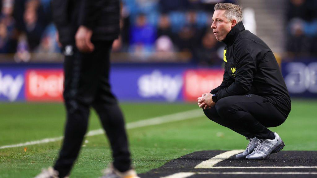 Neil Harris crouches down in the technical area while during Millwall's match against Sunderland