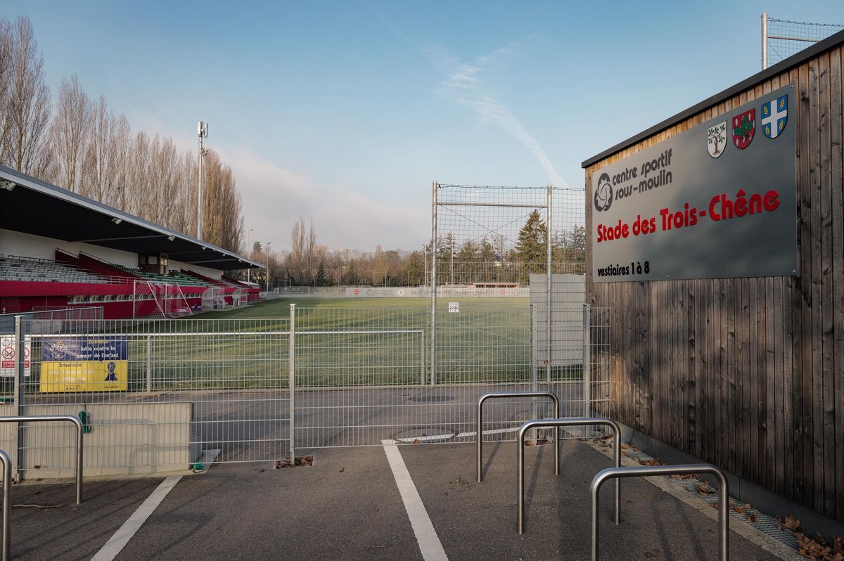 Vue du stade des Trois-Chênes au centre sportif de Sous-moulin à Thônex, Genève, avec des terrains de sport et une clôture.