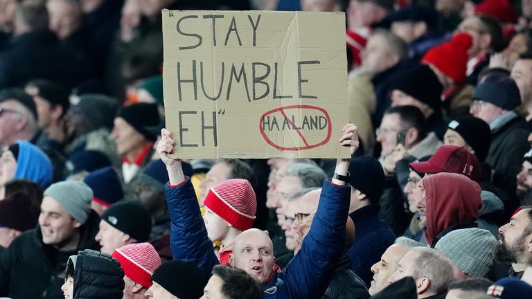 Un fan d'Arsenal brandit une pancarte 'stay humble' devant Erling Haaland