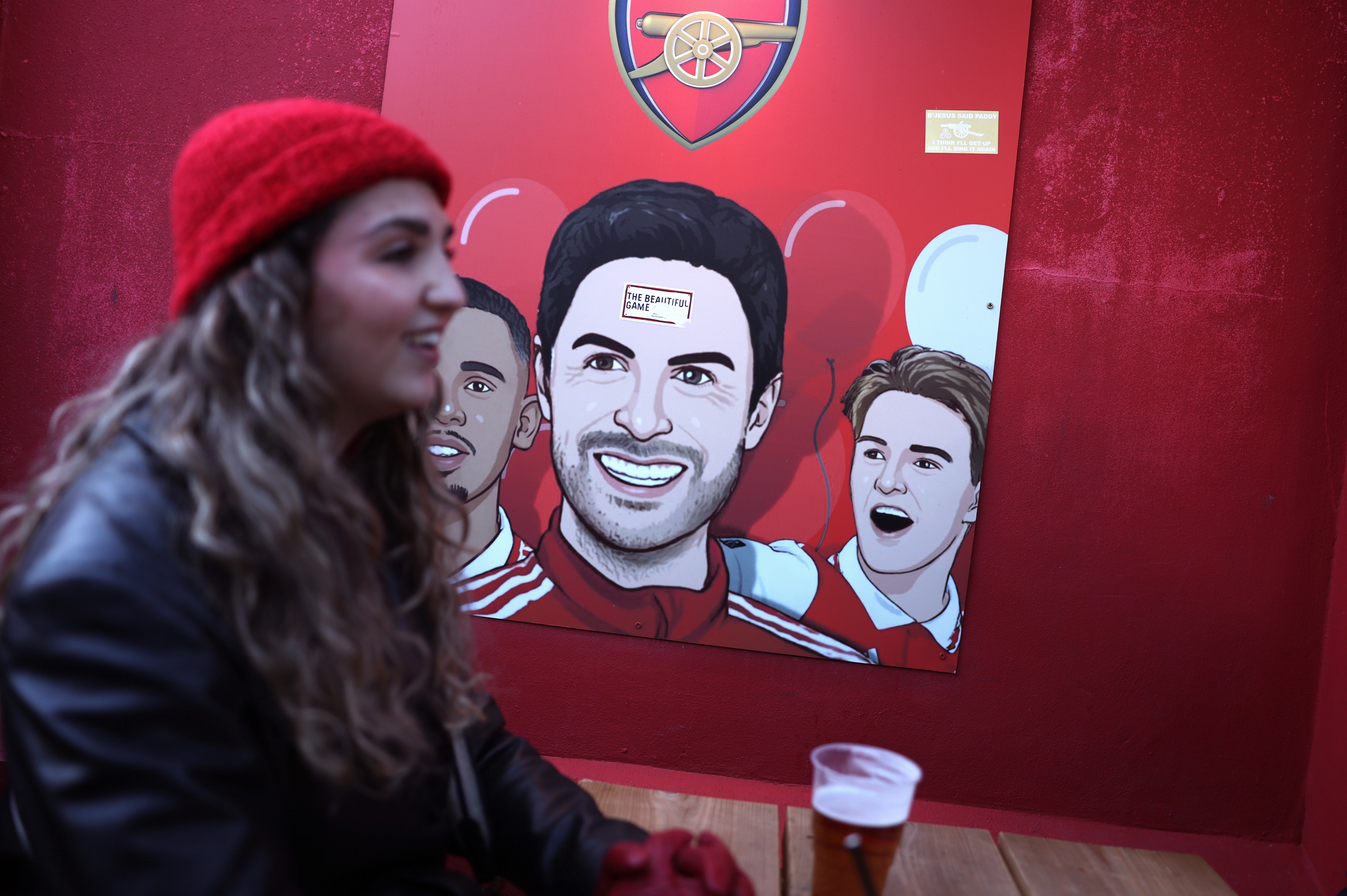 Fans sit in the Gunners Pub in-front of a Mikel Arteta sign