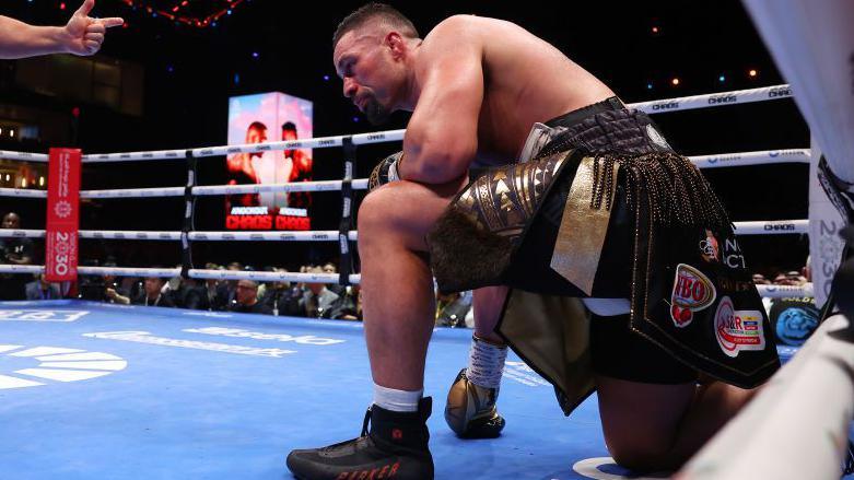 Joseph Parker à genoux, portant des chaussettes blanches sur le ring